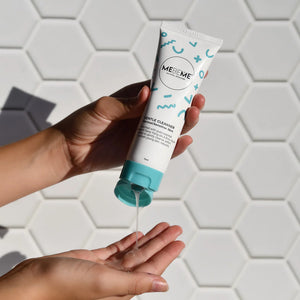Hand holding a MEBEME skincare product with a hexagonal tiled background