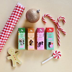 Assorted Christmas themed boxes for kids nail polish and lip gloss with Christmas decorations on a beige background