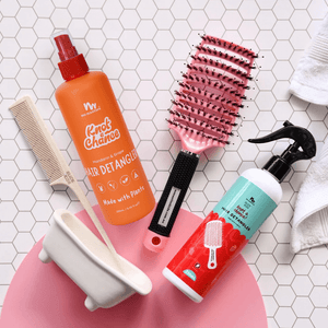 Hair care products including a bottle, brush, and comb on a tiled surface.