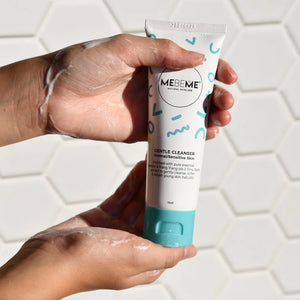 Hand holding a tube of MEBEME Gentle Cleanser against a tiled bathroom background