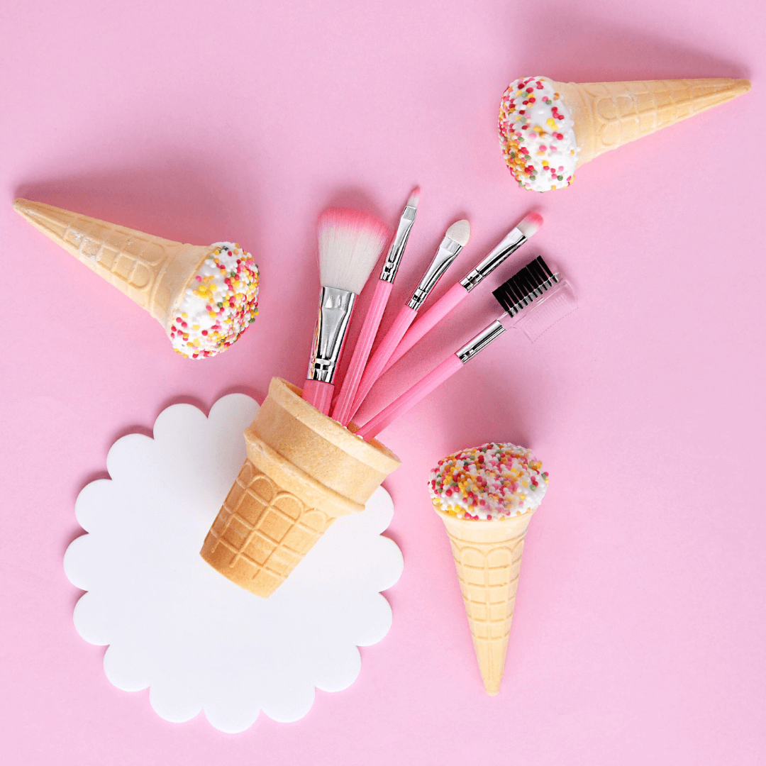 Makeup brushes in ice cream cone holders on a pink background