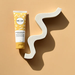 Tube of ME ME ME skincare product on a beige background with a wavy white object.