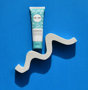 Tube of MEBEME hair product on a wavy grey stand against a blue background