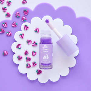 Purple lipgloss white flower with pink strawberry decorations on a purple background