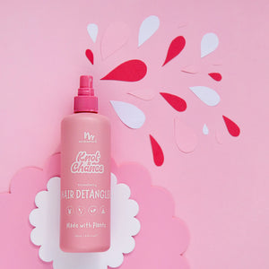 Pink hair detangler bottle with decorative elements on a pink background