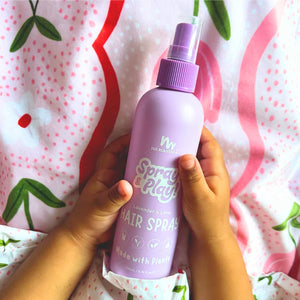 Purple hair spray bottle held by a person against a patterned background
