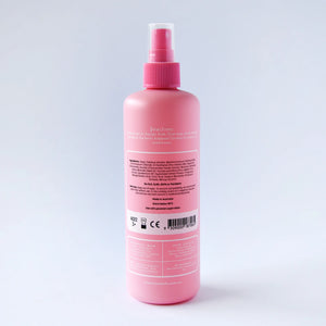Pink spray bottle with a label on a light gray background