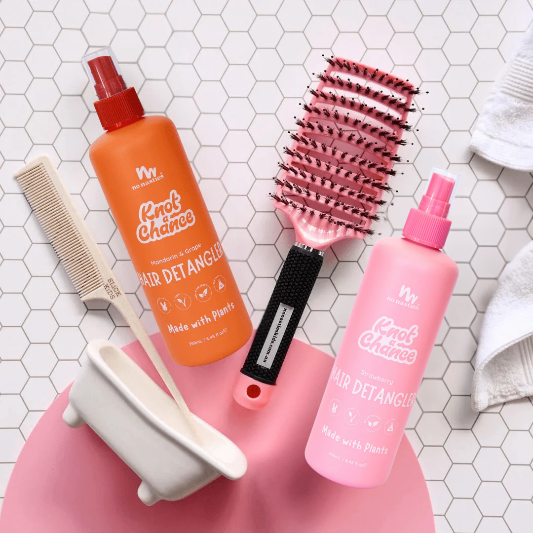 Hair care products including a detangler, brush, and comb on a tiled surface.