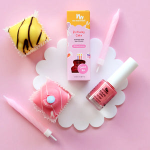 Birthday cake nail polish with packaging and birthday cake shaped items on a pink background