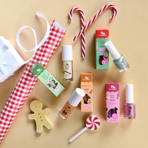 Lip gloss and nail polish for kids and festive items including candy canes, a gingerbread man cookie, and a lollipop on a beige background.