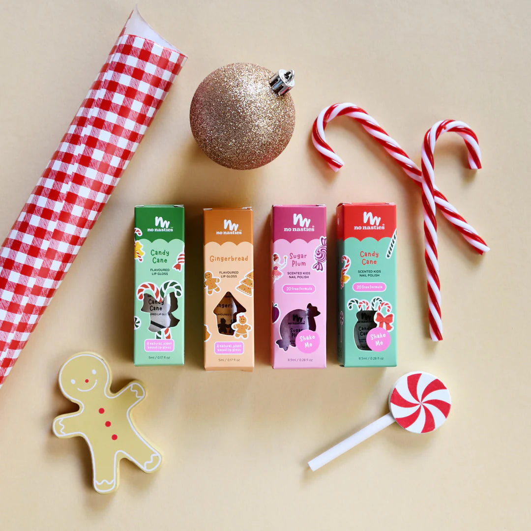 Lip gloss and nail polish for kids and festive items including candy canes, a gingerbread man cookie, and a lollipop on a beige background.