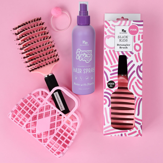 Pink hairbrush, hair spray, and packaging on a pink background