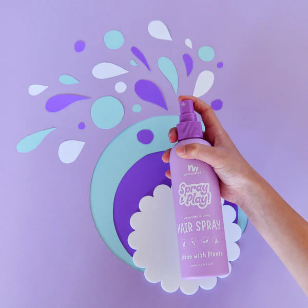 Hand holding a purple bottle of &#39;Spray &amp; Play&#39; hair spray against a light purple background with decorative elements.