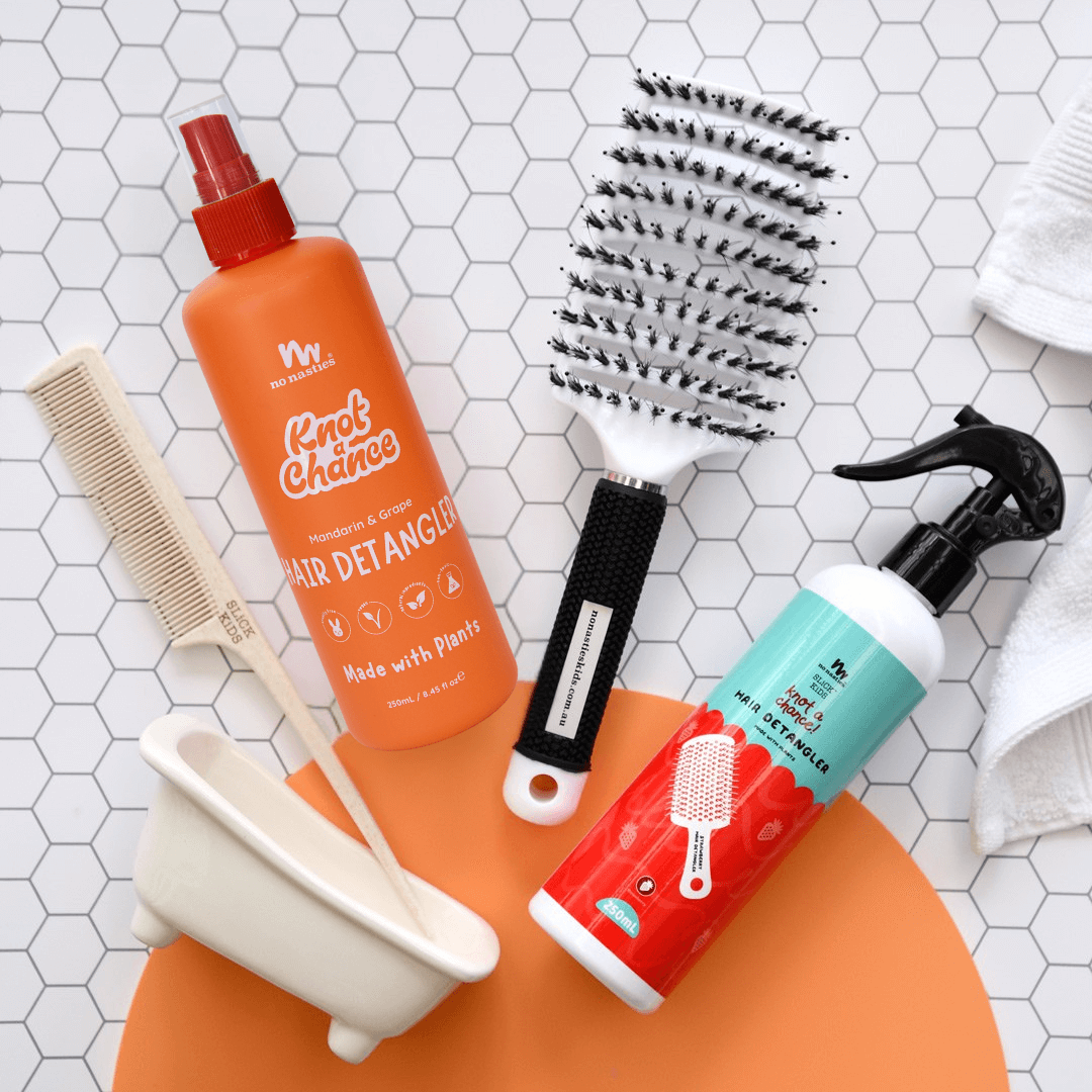Hair care products including a bottle, brush, and comb on a tiled surface