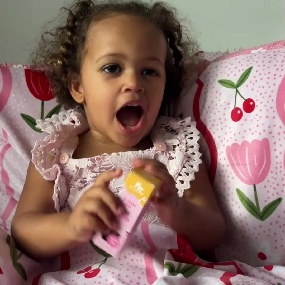 child holding a No Nasties Kids NZ Birthday Cake scented nail polish with cute pillow behind her