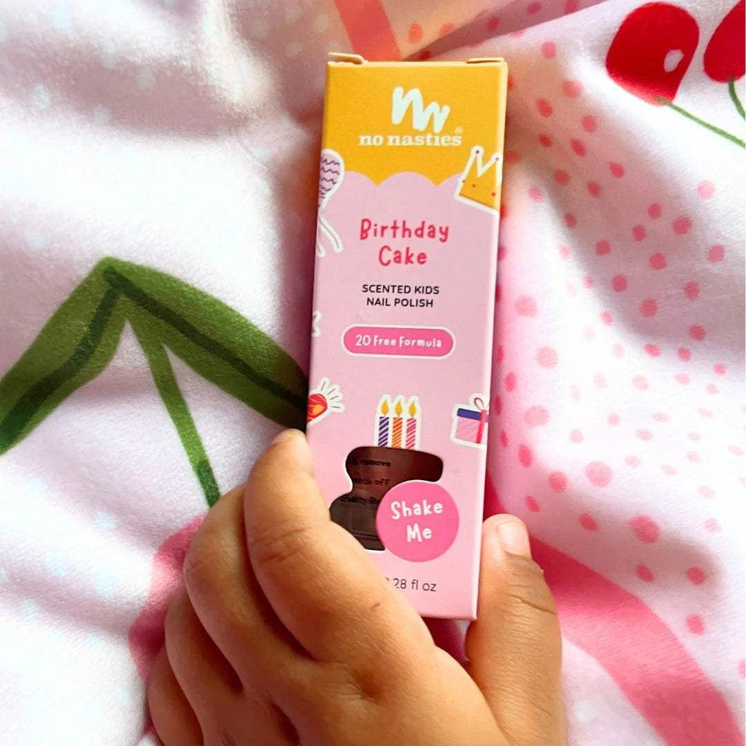 No Nasties Birthday Cake scented kids nail polish box held by a hand on a polka dot fabric background
