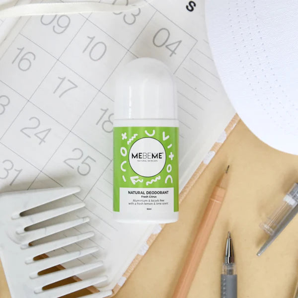 Mebeme natural deodorant bottle on a desk with a calendar and stationery items.