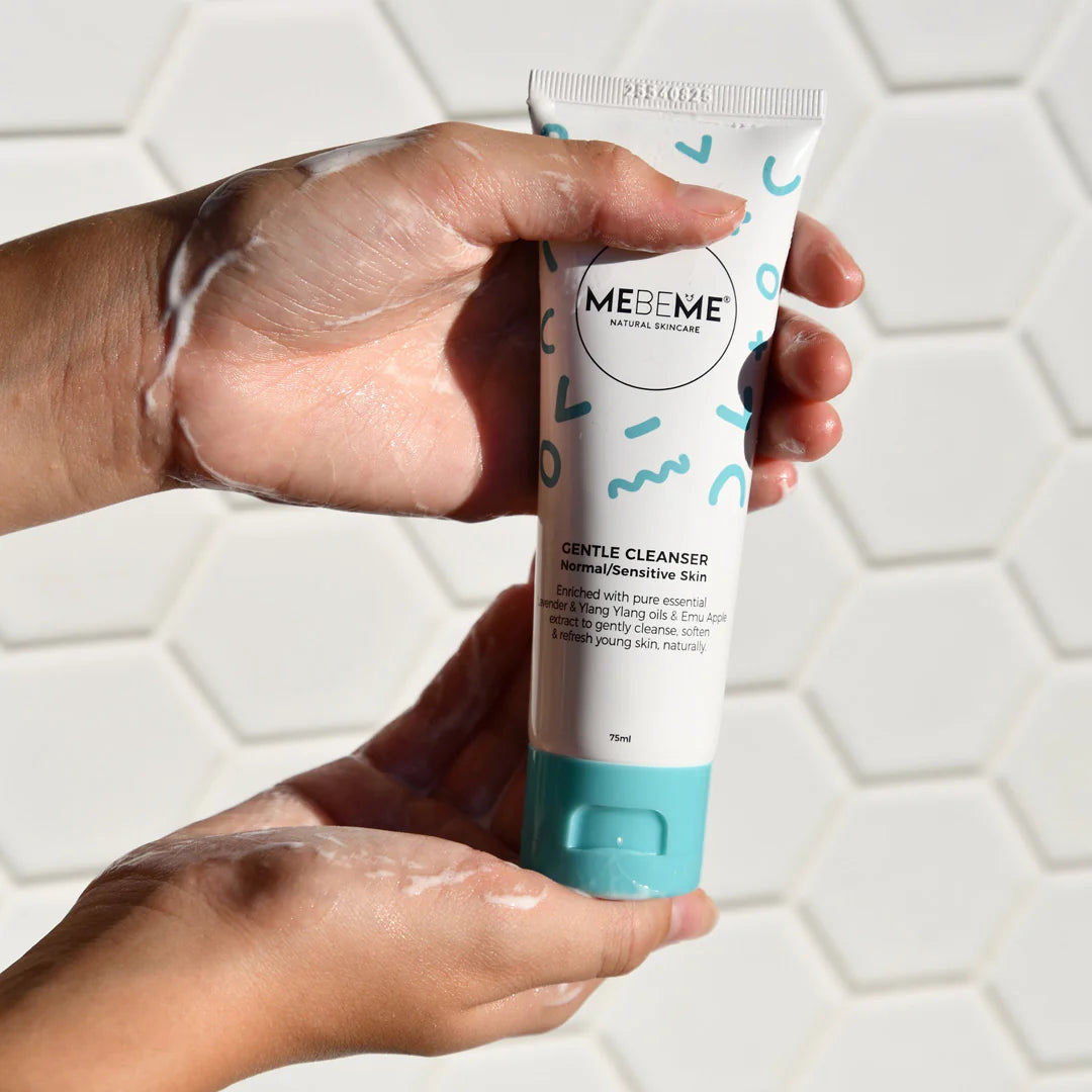 Hand holding a tube of MEBEME Gentle Cleanser against a tiled bathroom background