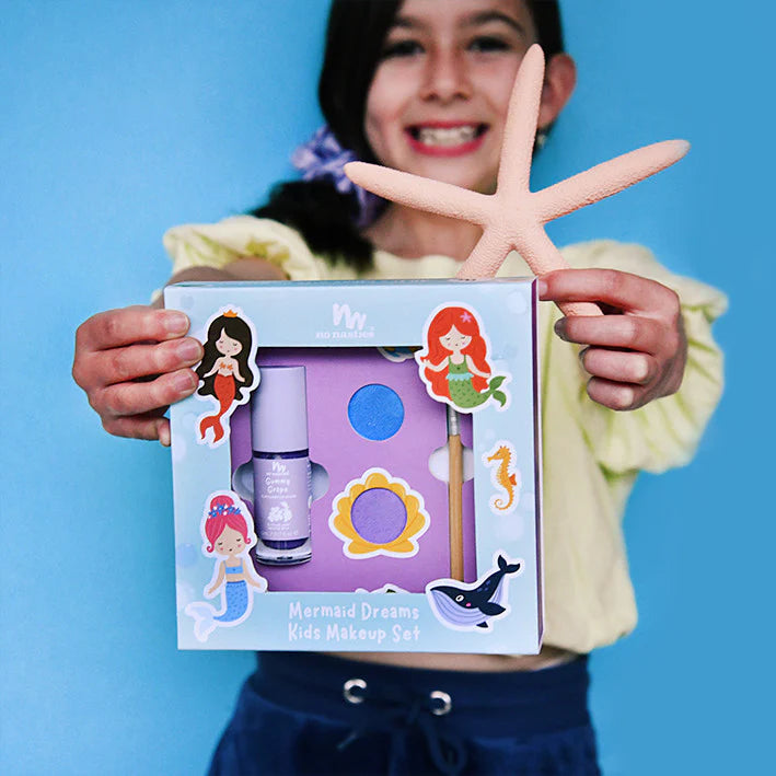 Child holding a mermaid themed makeup set from No Nasties Kids NZ against a blue background