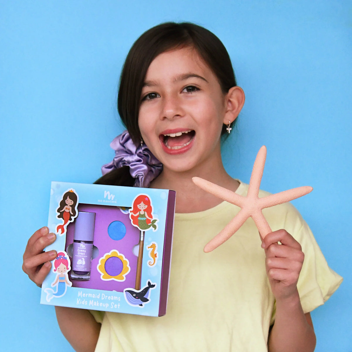 Girl holding a makeup set and starfish against a blue background
