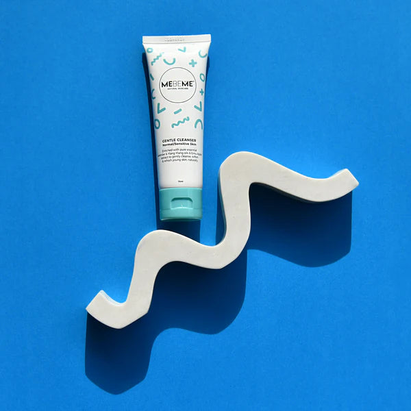 Tube of MEBEME Gentle Cleanser on a wavy white stand against a blue background