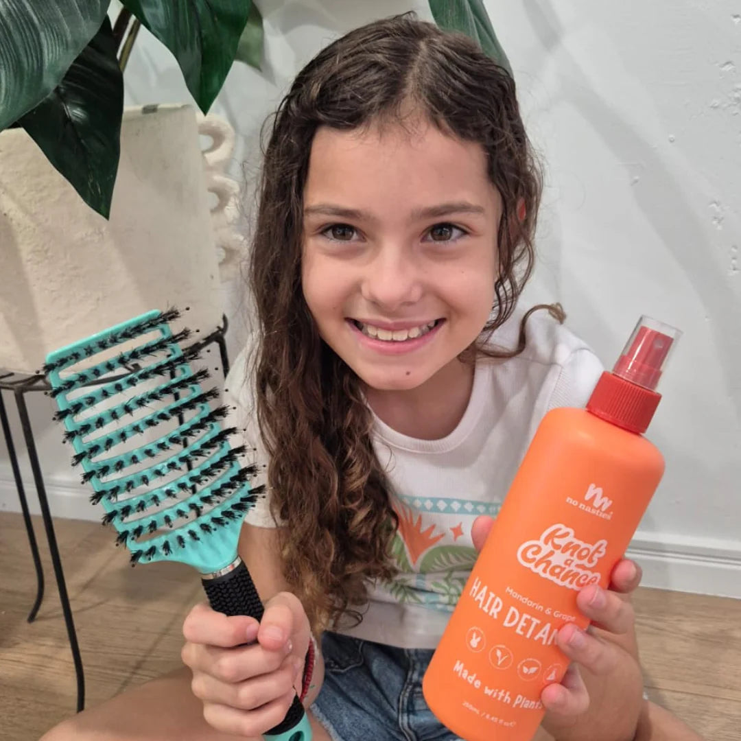 Girl holding No Nasties Kids NZ detangler spray and hair brush 