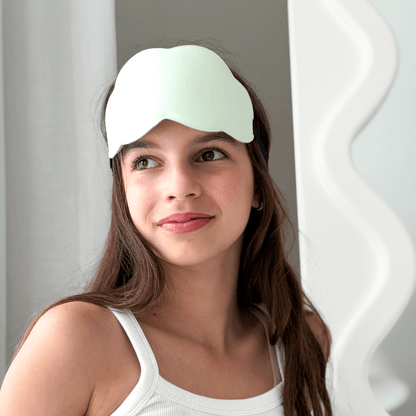 Tween wearing a light green sleep mask against a neutral background