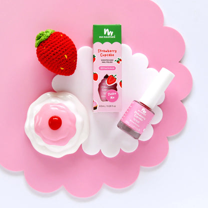 Strawberry scented kids nail polish and strawberry shaped item on a pink flower shaped background.