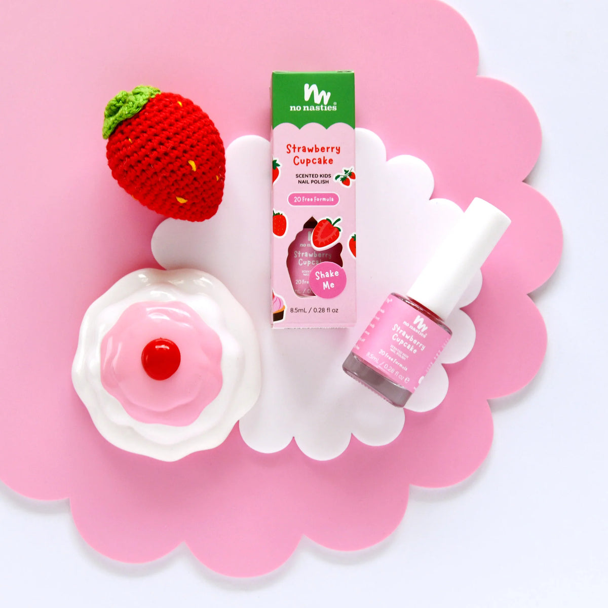 Strawberry scented kids nail polish and strawberry shaped item on a pink flower shaped background.