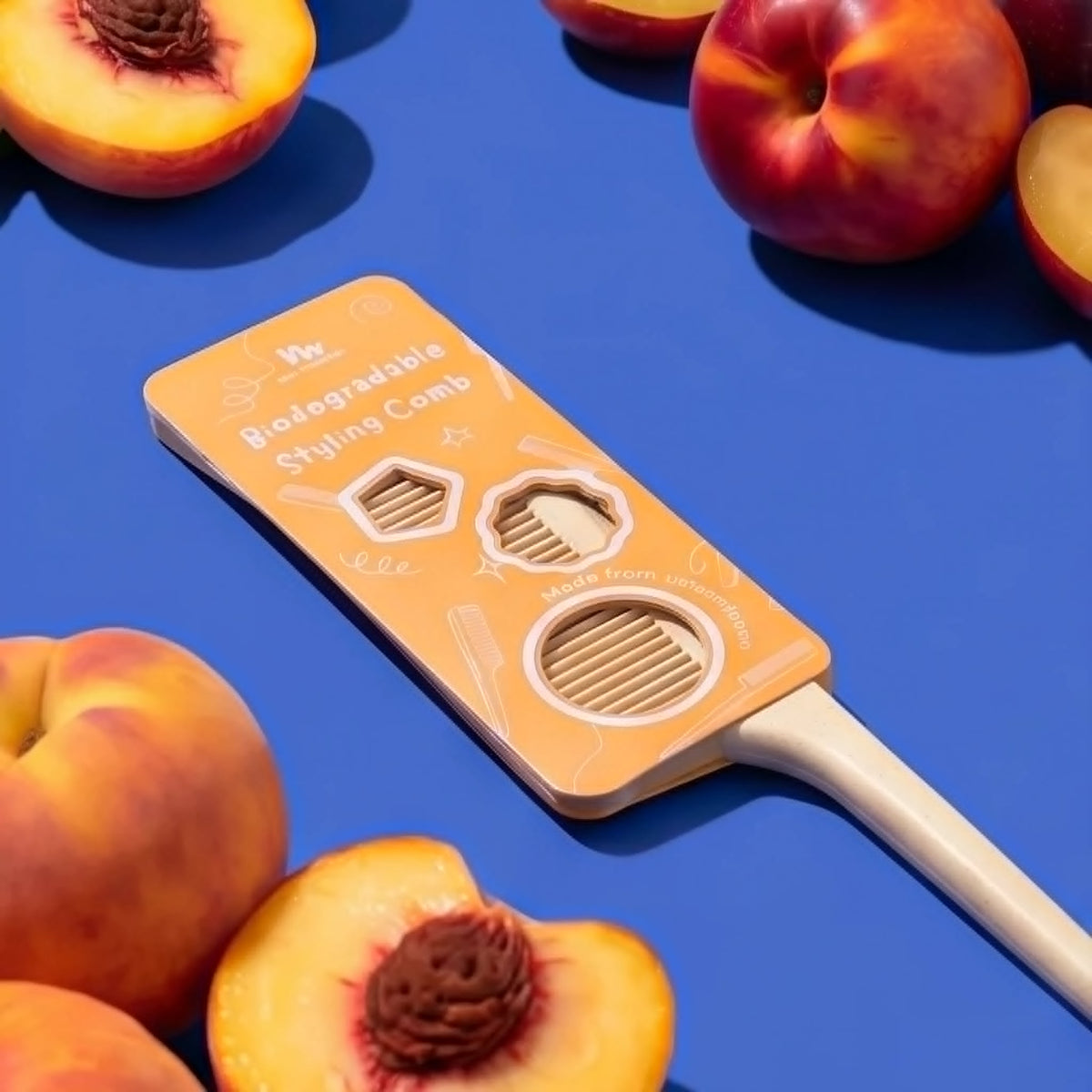 A reusable hair comb, packaging features a cutout slot and printed text, styled on a vibrant blue background with fresh peaches around it.