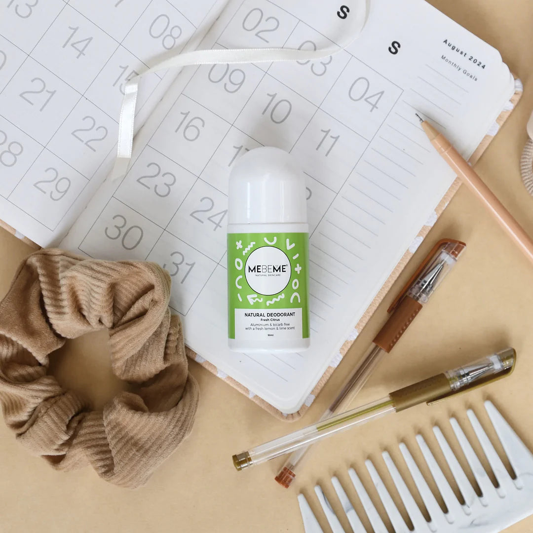 Mebeme natural deodorant bottle on a desk with a calendar and stationery items.