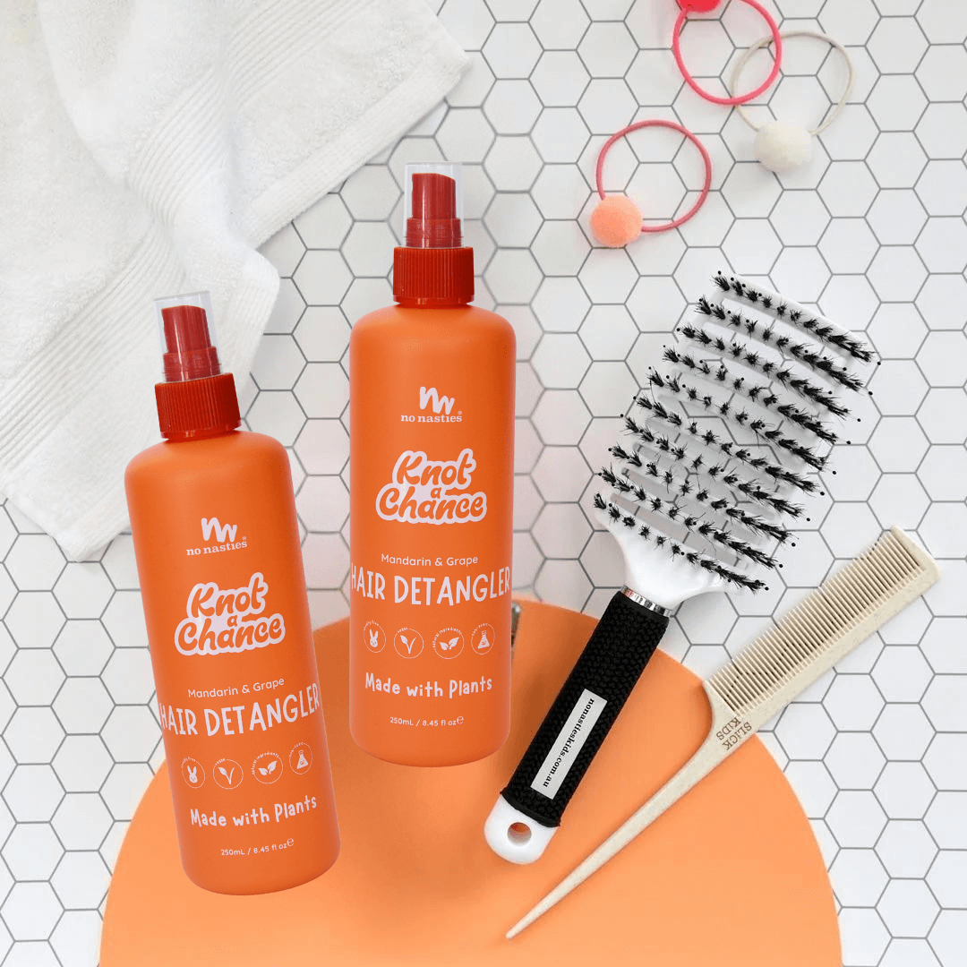 Two bottles of 'Knot Chance' hair detangler with a comb and brush on a white tiled background.