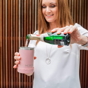 Woman pouring sparkling wine into pink can and bottle cooler used as a cup