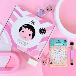 Pink makeup set for kids eyeshadow nail stickers and makeup brush laid out on pink background