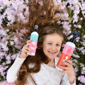 girl-with-long-hair-laying-in-field-of-flowers-holding-hair-spray-and-detangler-spray